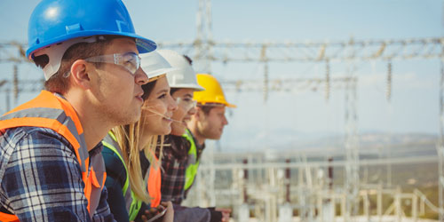 Start Berufswelt Drei Ingenieure schauen in die Ferne vor einer Baustelle.