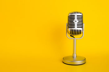 Ein altes Mikrofon steht auf gelbem Grund.